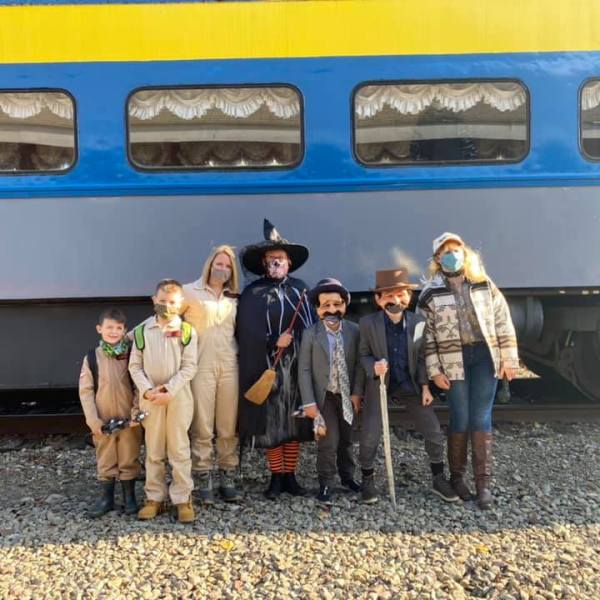 a group of people standing in front of a blue train